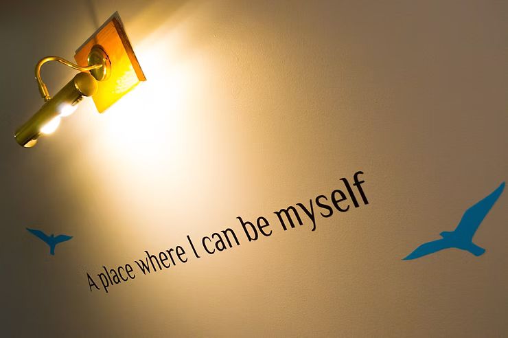 "A place where I can be myself" painted on a wall, under a warm light